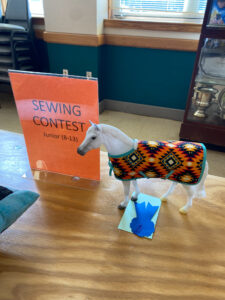 A miniature plastic horse in a sewn coat.